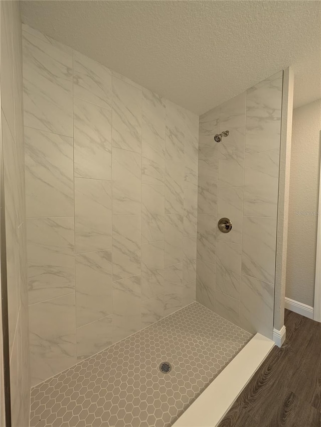 14259 SE 33rd Ter, Summerfield, FL 34491 - full bathroom featuring a tile shower, baseboards, wood finished floors, and a textured ceiling
