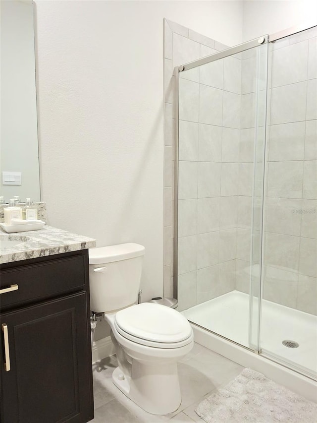 bathroom featuring vanity, tile patterned flooring, a shower with shower door, and toilet