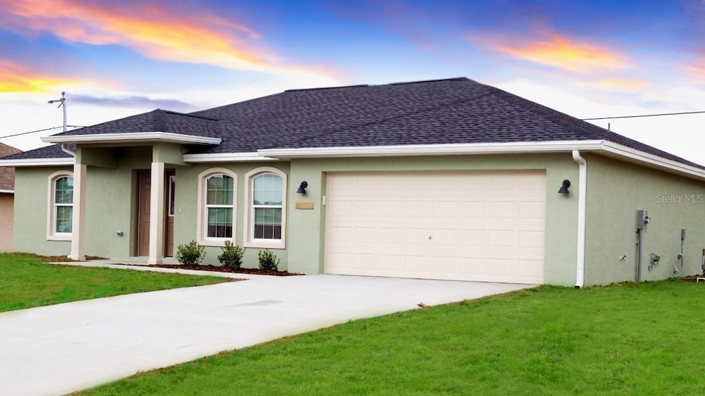 ranch-style home with a garage and a lawn