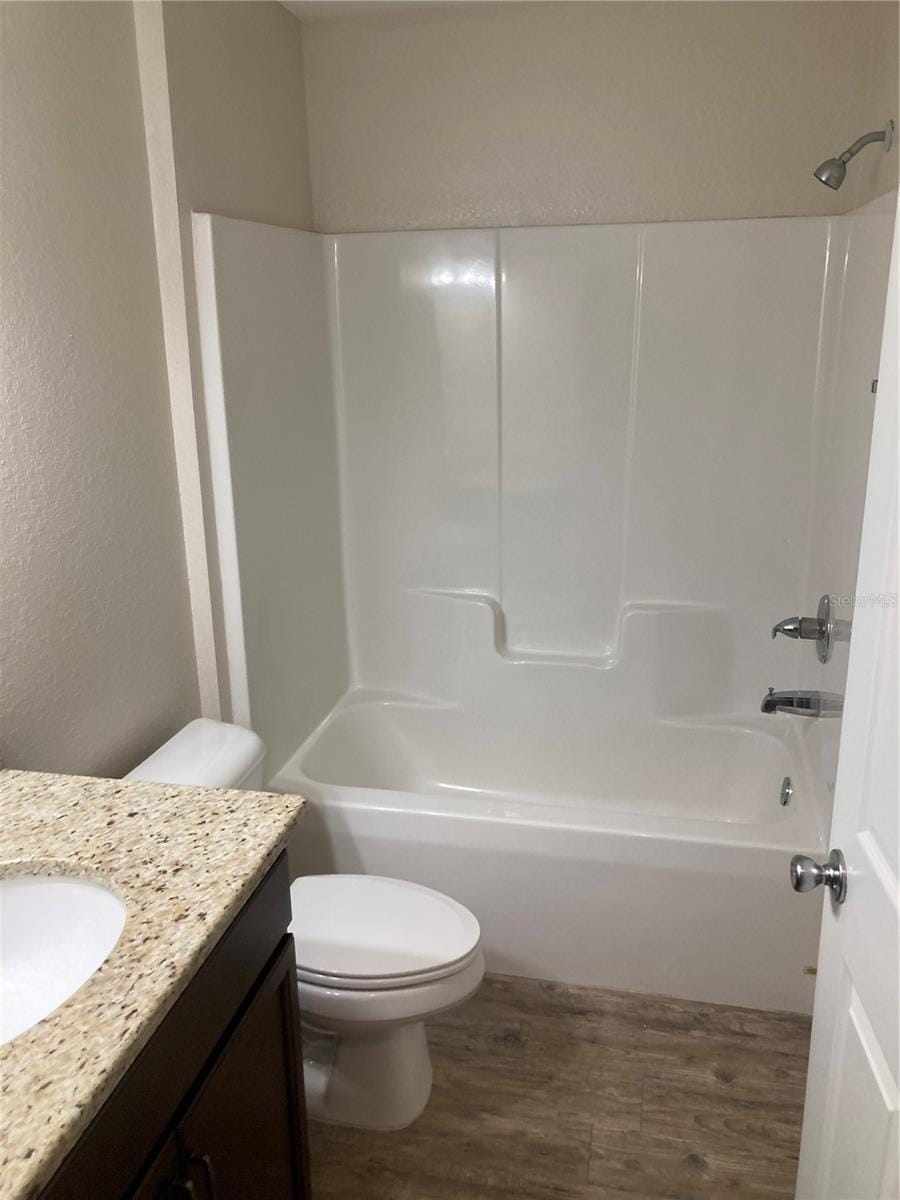 full bathroom featuring vanity, wood-type flooring, bathtub / shower combination, and toilet