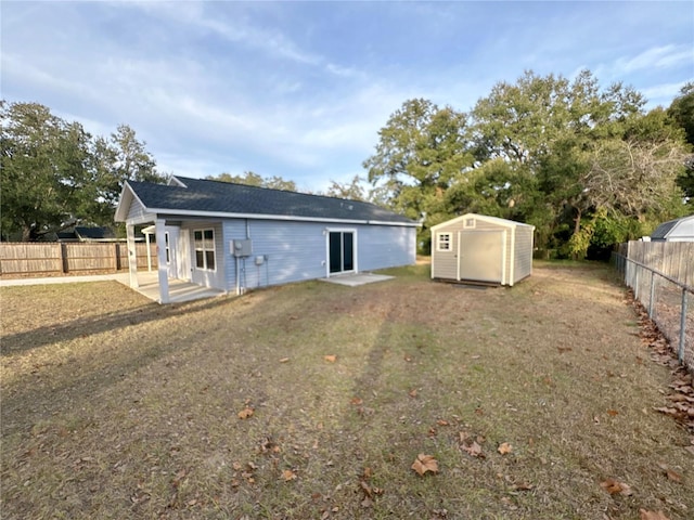 back of house with a storage unit and a lawn