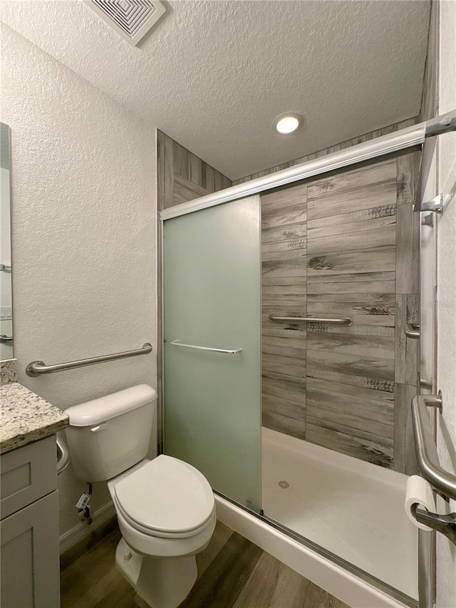 bathroom featuring wood-type flooring, toilet, vanity, and a textured ceiling