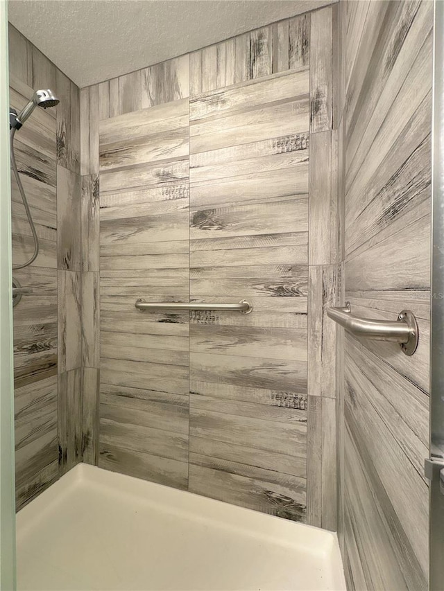 bathroom featuring a tile shower and a textured ceiling