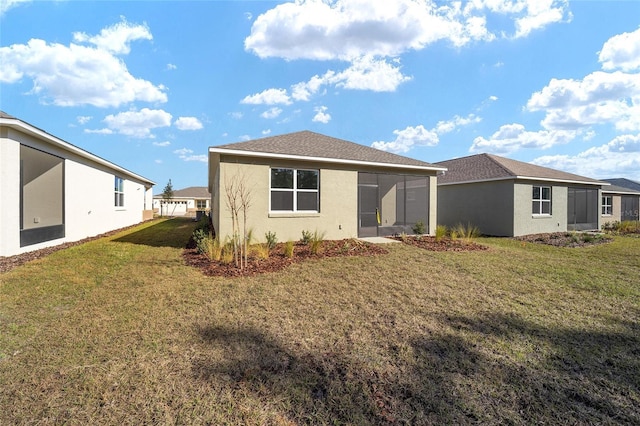 rear view of property featuring a sunroom and a lawn