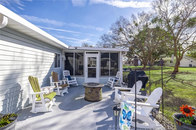 view of patio / terrace with area for grilling, a sunroom, and a fire pit