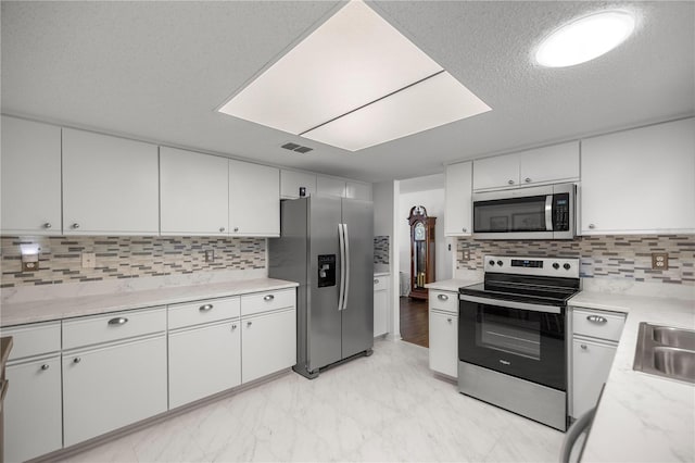 kitchen featuring backsplash, stainless steel appliances, and white cabinets