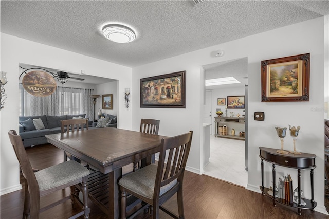 dining room featuring ceiling fan, dark wood-type flooring, and a textured ceiling