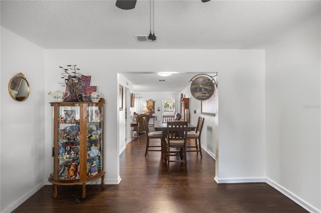 dining area featuring dark wood-type flooring and a textured ceiling