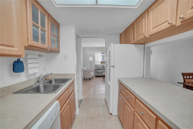 kitchen with sink, light tile patterned floors, light brown cabinetry, and white appliances