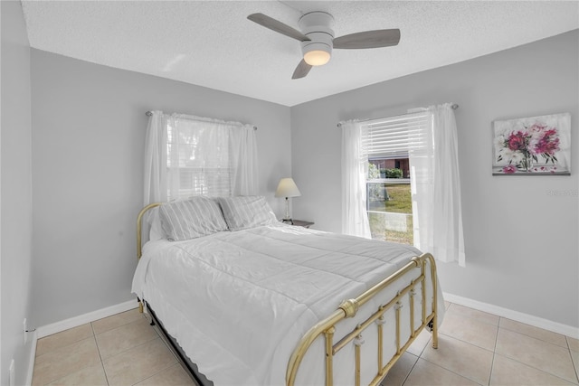 tiled bedroom with ceiling fan and a textured ceiling