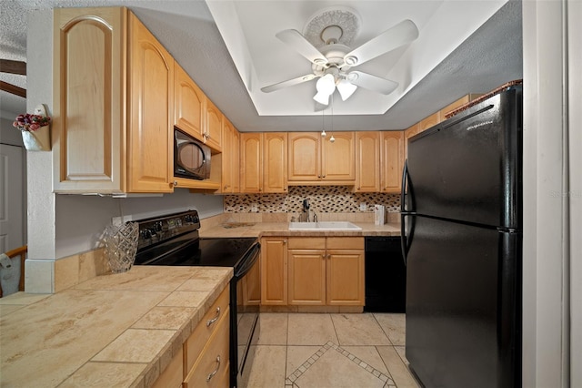 kitchen featuring a raised ceiling, sink, light brown cabinetry, and black appliances