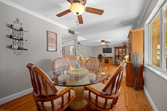 dining room featuring ceiling fan, ornamental molding, a textured ceiling, and light wood-type flooring