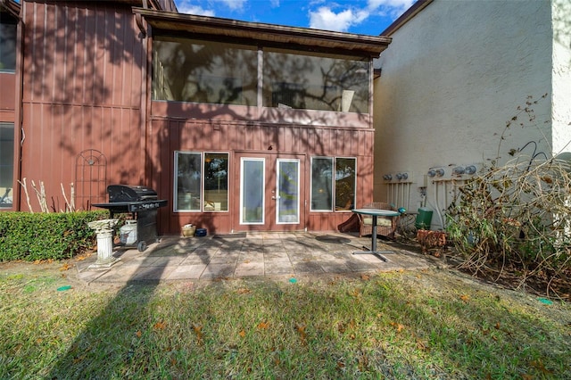 back of property featuring french doors, a lawn, and a patio area