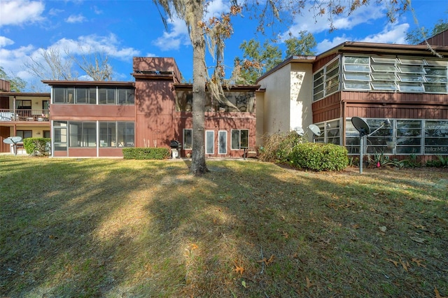 back of house with a lawn and a sunroom