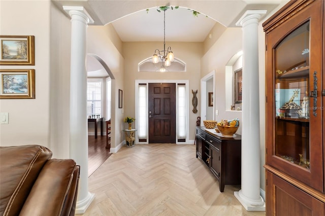 entryway with light parquet floors, an inviting chandelier, and ornate columns