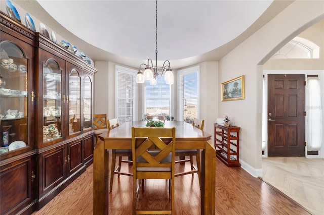 dining space with hardwood / wood-style floors and a notable chandelier