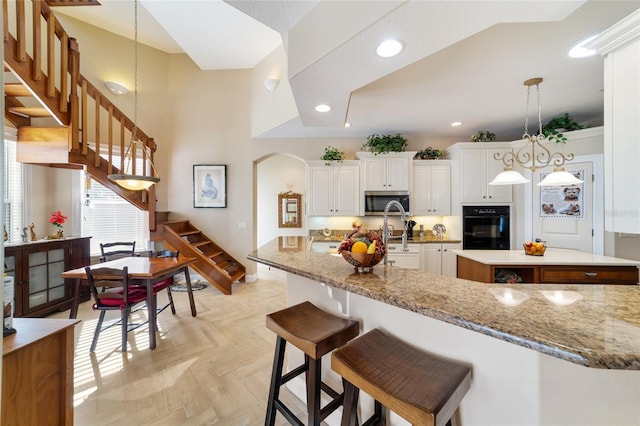 kitchen with hanging light fixtures, light parquet flooring, oven, and white cabinets