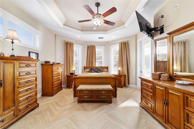 bedroom with crown molding, a tray ceiling, and light parquet flooring