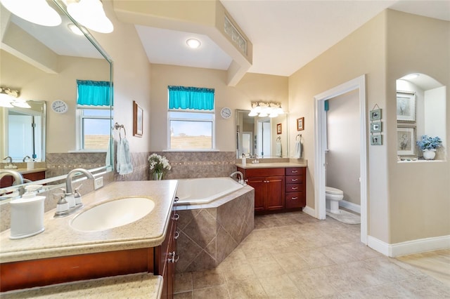 bathroom with vanity, toilet, and tiled bath