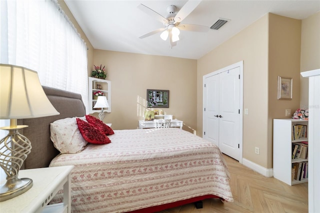 bedroom with light parquet floors, ceiling fan, and a closet