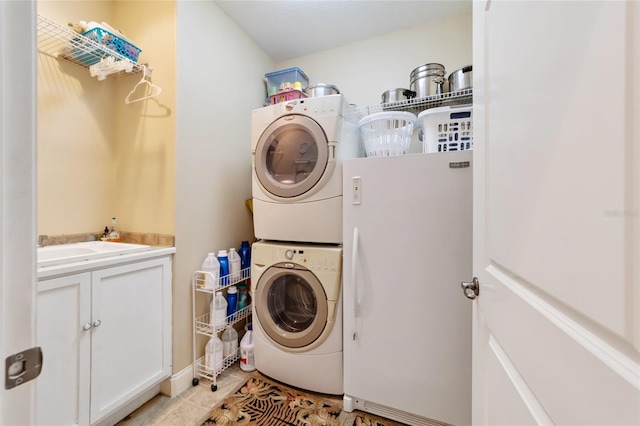 clothes washing area featuring cabinets, stacked washer and clothes dryer, and light tile patterned floors