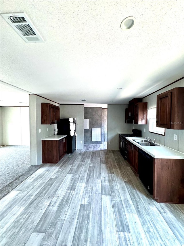 kitchen featuring sink, dark brown cabinetry, black appliances, a textured ceiling, and light wood-type flooring