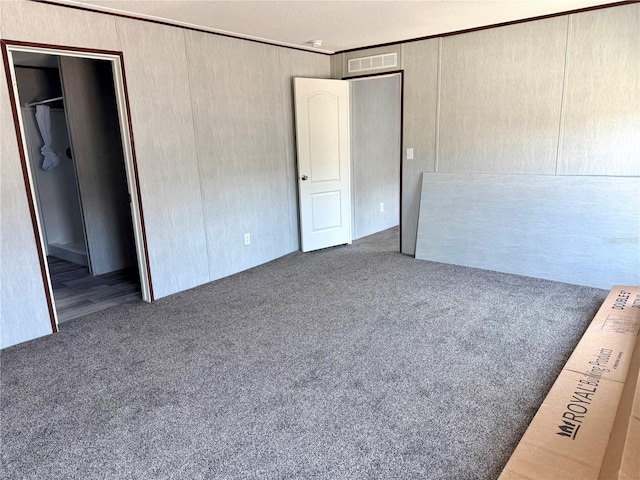 unfurnished bedroom featuring crown molding, dark carpet, and a closet