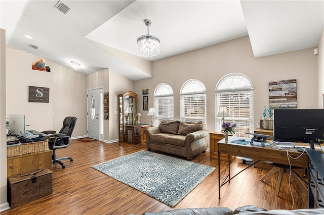 office space featuring lofted ceiling, a notable chandelier, wood-type flooring, and a textured ceiling