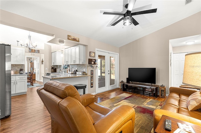 living room with french doors, lofted ceiling, ceiling fan with notable chandelier, and wood-type flooring