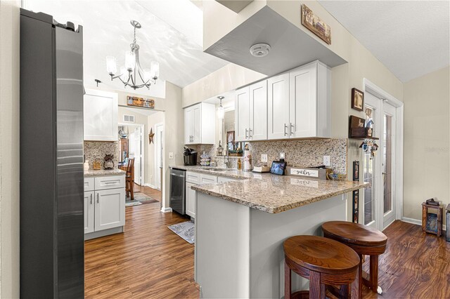 kitchen with light stone countertops, dark hardwood / wood-style floors, pendant lighting, and white cabinets