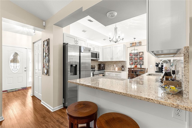 kitchen with a kitchen bar, kitchen peninsula, white cabinets, and appliances with stainless steel finishes