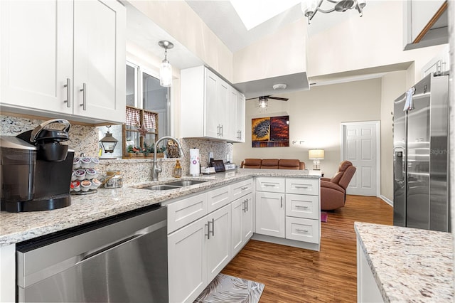 kitchen with pendant lighting, sink, hardwood / wood-style floors, stainless steel appliances, and white cabinets