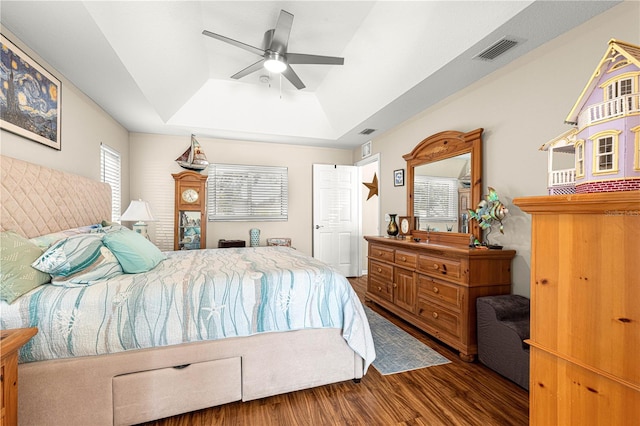 bedroom featuring dark hardwood / wood-style flooring, a raised ceiling, and ceiling fan