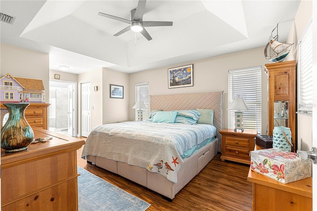 bedroom featuring dark wood-type flooring, ceiling fan, a tray ceiling, and a closet