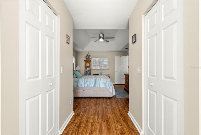 unfurnished bedroom featuring ceiling fan, dark hardwood / wood-style flooring, and a tray ceiling