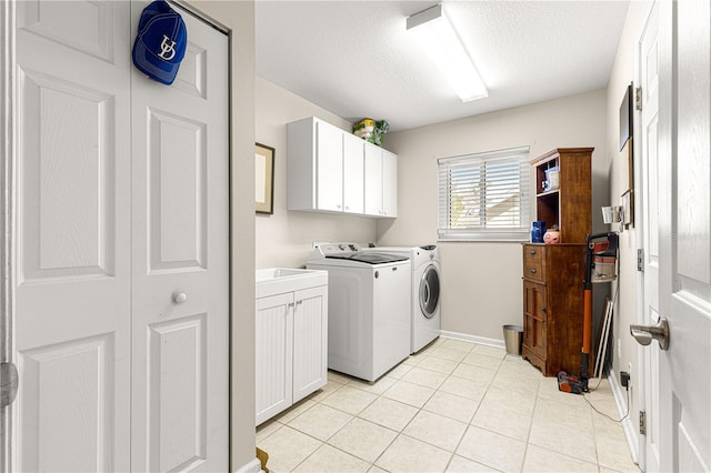 washroom with light tile patterned flooring, cabinets, washer and dryer, and a textured ceiling