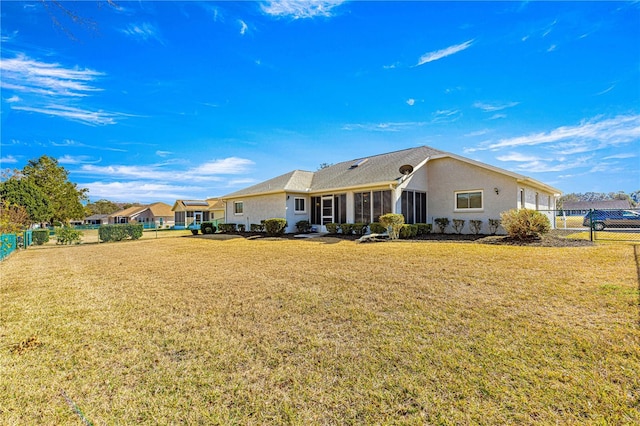 rear view of house with a sunroom and a lawn