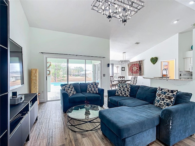 living room with an inviting chandelier, sink, lofted ceiling, and light wood-type flooring