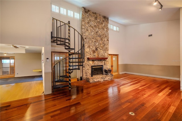 living room featuring track lighting, wood-type flooring, a fireplace, and a high ceiling