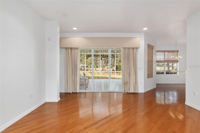 unfurnished room with a chandelier and hardwood / wood-style floors