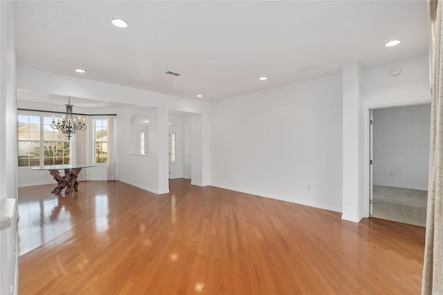 unfurnished living room with an inviting chandelier and light wood-type flooring