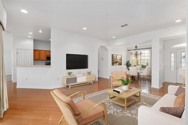 living room with an inviting chandelier and light hardwood / wood-style flooring