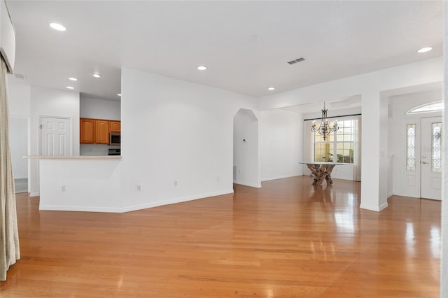 unfurnished living room with a chandelier and light wood-type flooring