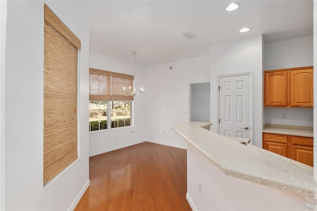 kitchen featuring pendant lighting, wood-type flooring, and a chandelier