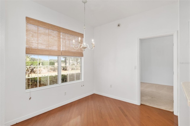 unfurnished dining area with a notable chandelier and hardwood / wood-style flooring