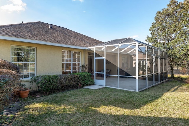 back of house featuring a patio area, glass enclosure, and a lawn