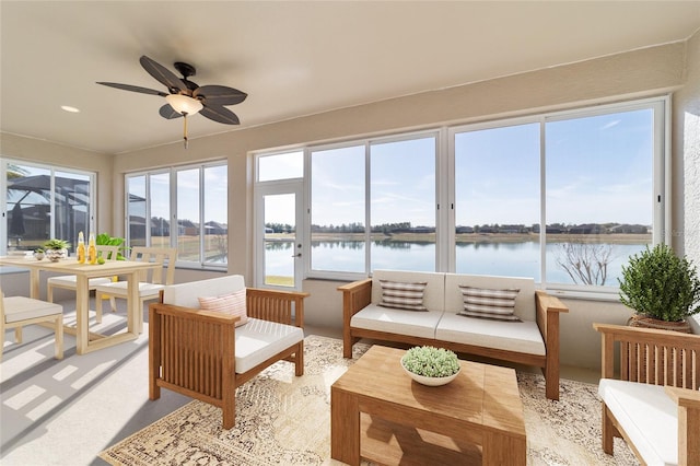 sunroom / solarium with ceiling fan and a water view