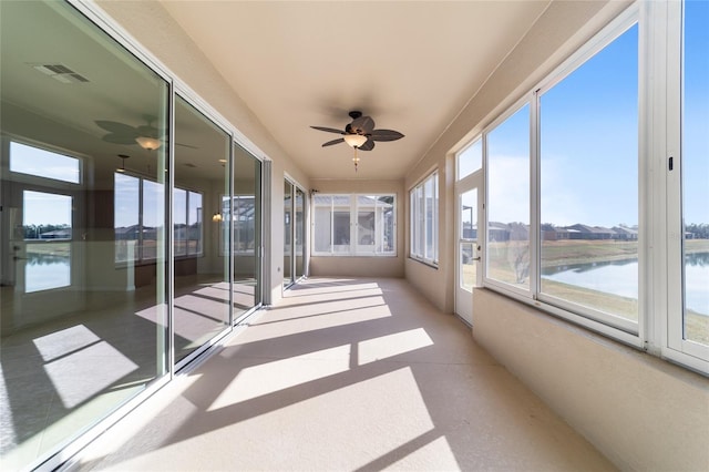 unfurnished sunroom featuring ceiling fan and a water view