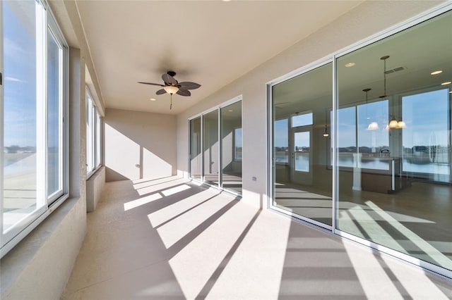 unfurnished sunroom with a water view and ceiling fan