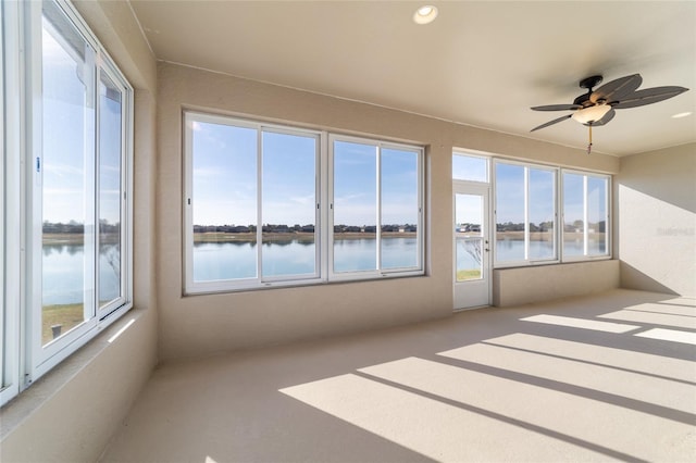 unfurnished sunroom with ceiling fan and a water view